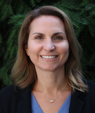 Natalie Laudier, straight brown hair, brown eyes, wearing a blue blouse and a black jacket