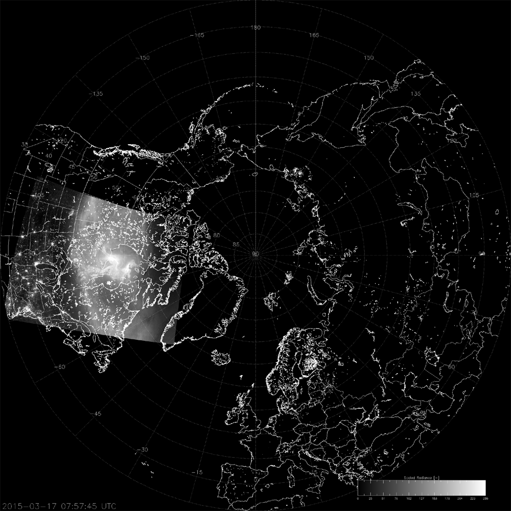 Animated satellite imagery from the VIIRS Day/Night Band showing a bright aurora circling around the Arctic region. The view is centered over the North Pole. The aurora appears as a glowing, shifting white arc, against a dark nighttime backdrop. City lights are also visible across parts of North America and Europe.