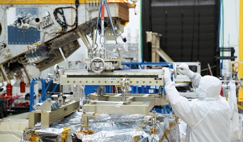 An engineer inspects the crane that is suspending the VIIRS instrument