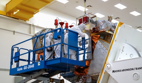 Engineers on scaffolding integrating ATMS instrument to the satellite main bus.
