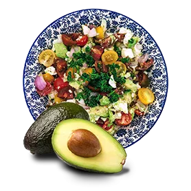 Avocado half in front of a plate with colorful food