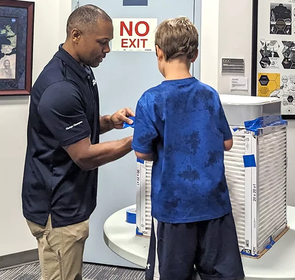 Photo of adult man and boy as they assemble and tape together a constructed box.