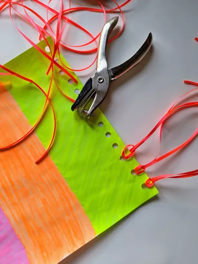Close-up photo of a hole puncher and partially constructed windsock.