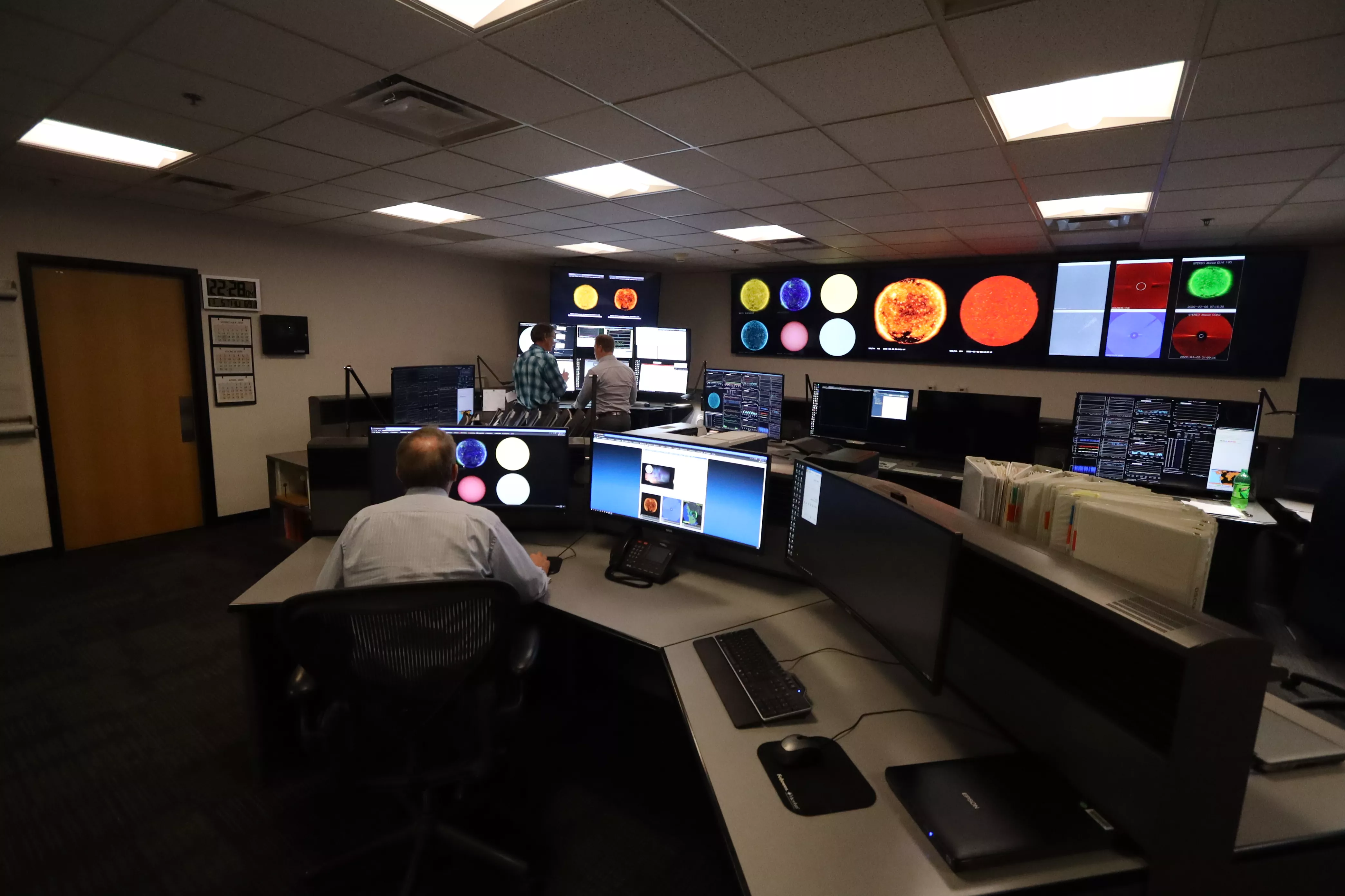 People in the space weather center looking at a row of computer screens.