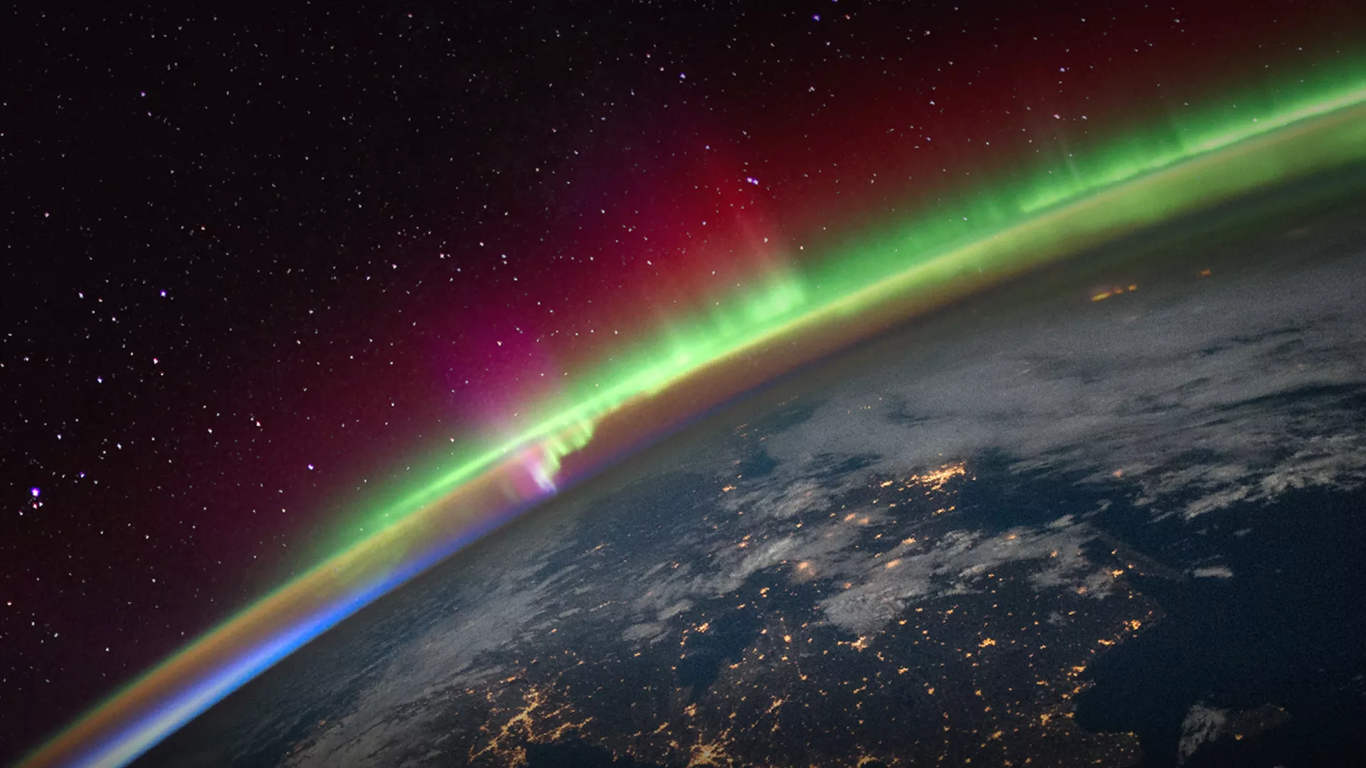 Earth seen from space with the aurora borealis in the background.