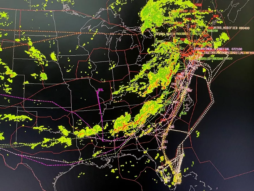 This visualization shows rerouted air traffic (depicted as dotted lines) around storms in the Eastern U.S. Green, yellow, orange, and red shading indicate the presence of storms from weather radar.