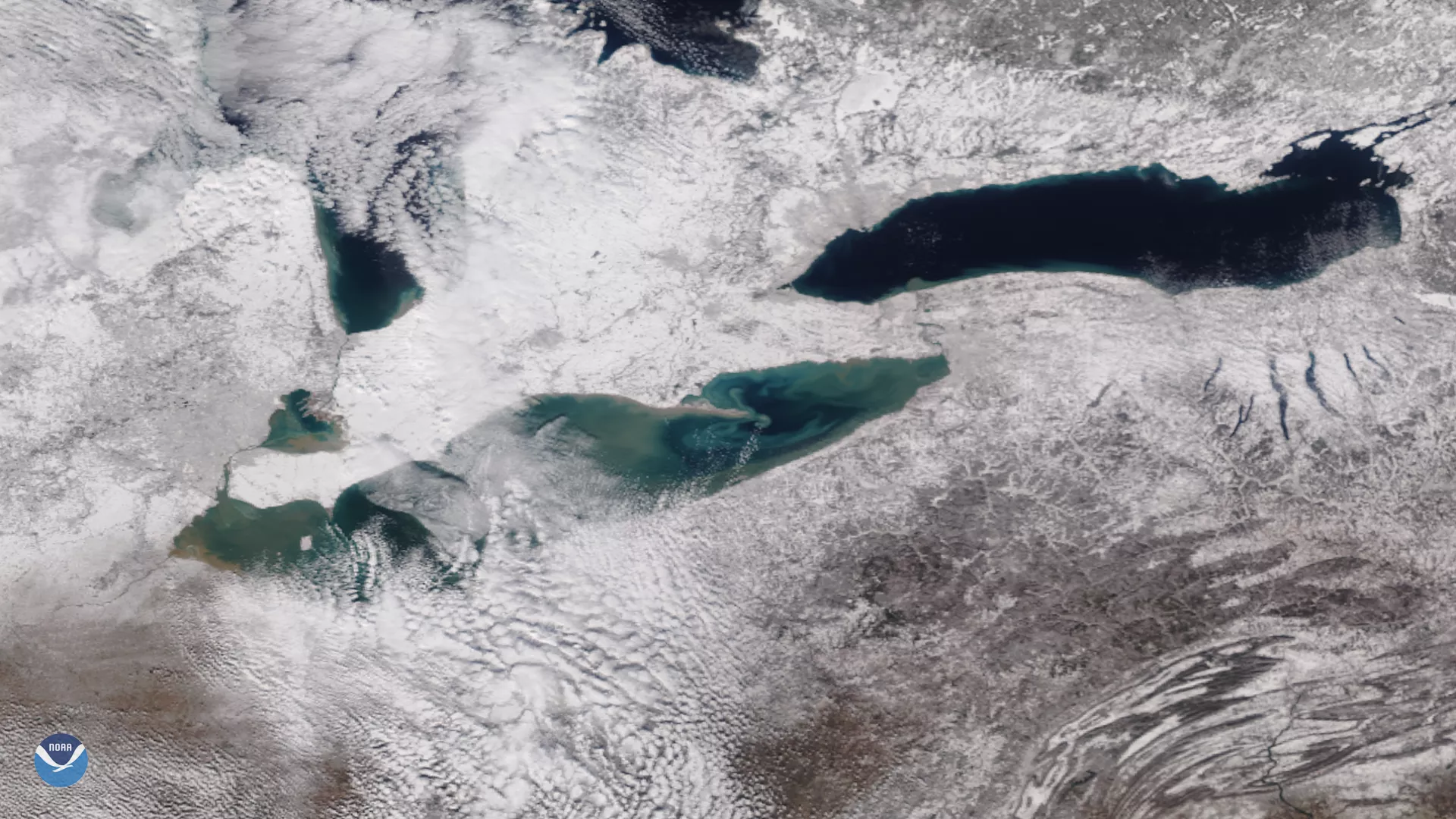 A NOAA-20 satellite view of Lake Erie with Lake Huron to its north (under some cloud cover) and Lake Ontario to its northeast, in TrueColor.